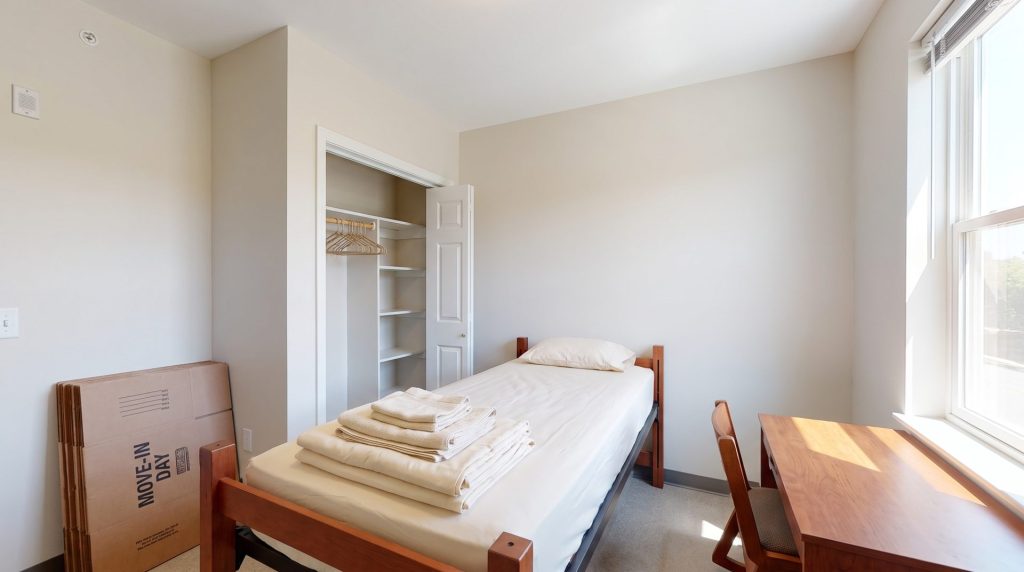 Clean empty college dorm room with made bed and moving boxes ready for move-in day near Glassboro, New Jersey
